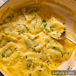 spoon holding a parcel of ravioli in pot of pasta in squash sauce