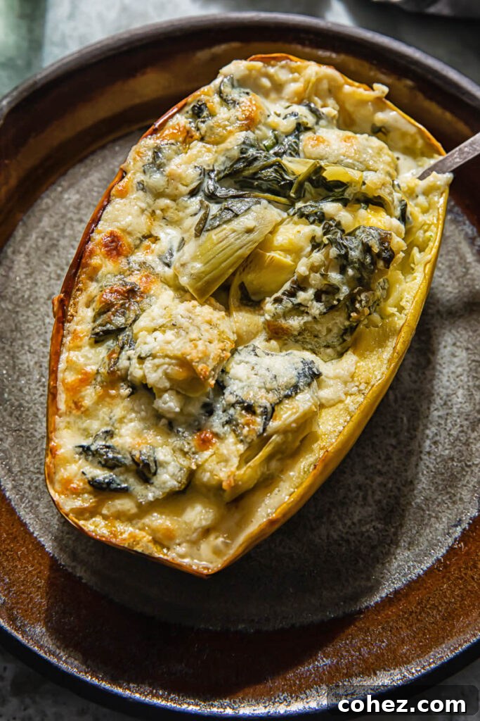 Two halves of spaghetti squash stuffed with creamy spinach and artichoke filling, garnished with fresh herbs, on a white plate
