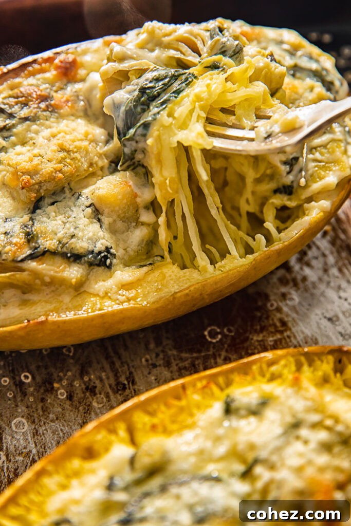 Close-up of baked spaghetti squash filled with melted cheese, spinach, and artichoke, showcasing the golden-brown crust