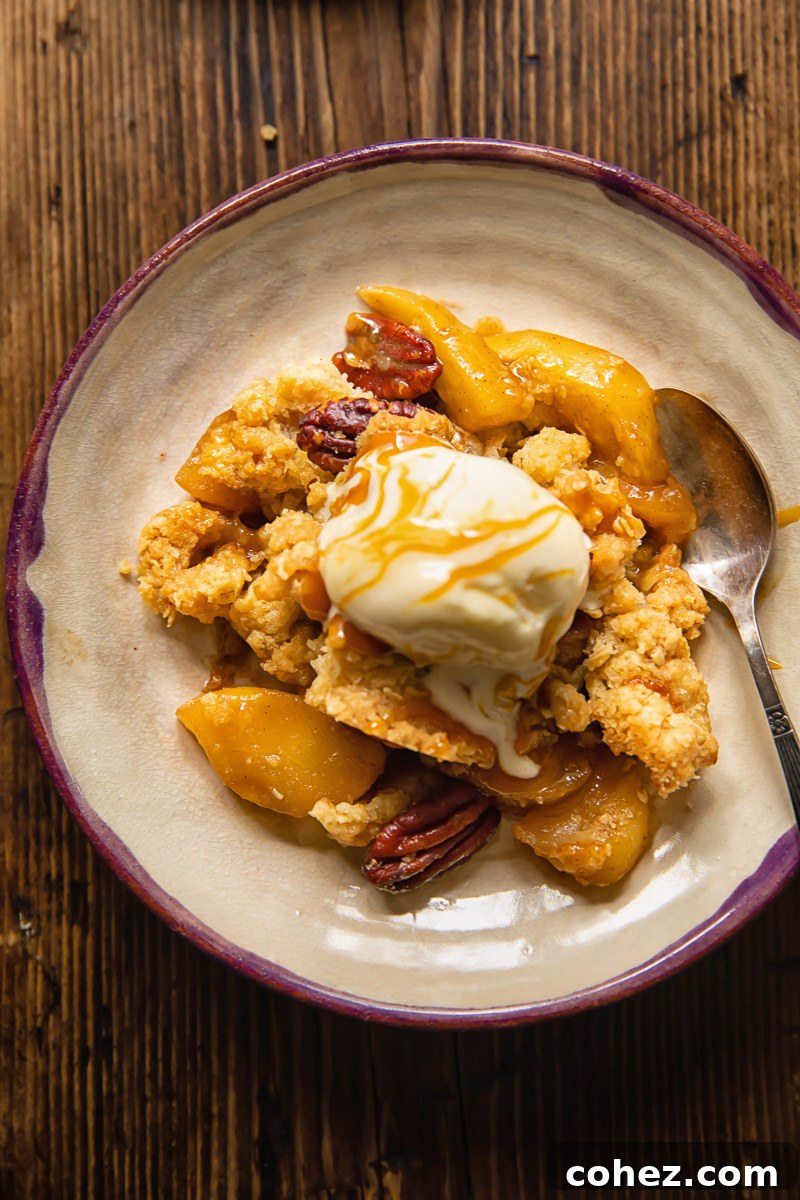 Top down view of a piece of apple cisp on a plate served with ice cream and pecans on top