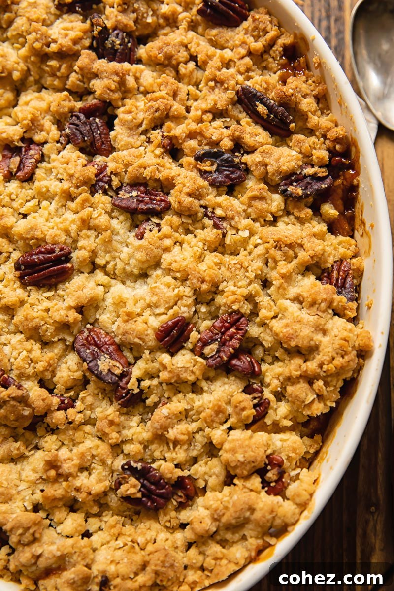 Clopse up shot of Apple Crisp topped with oatey crisp and pecans in a baking dish