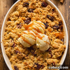 Top down view of ice cream on a apple crisp topped with pecans in a baking dish