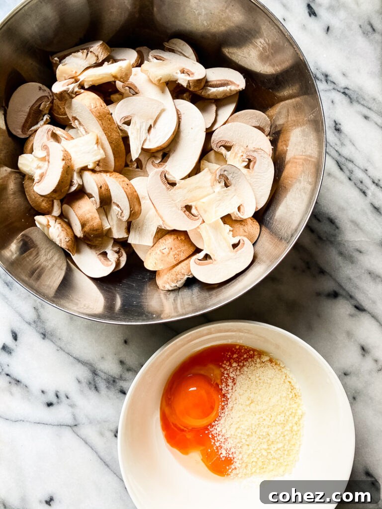 Top down of mushrooms in silver bowl next to bowl with one egg and cheese