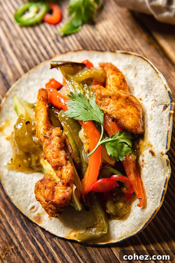 A vibrant top-down view of a freshly prepared chicken fajita, showcasing tender chicken, roasted peppers, and a dollop of fresh salsa, ready to be enjoyed.