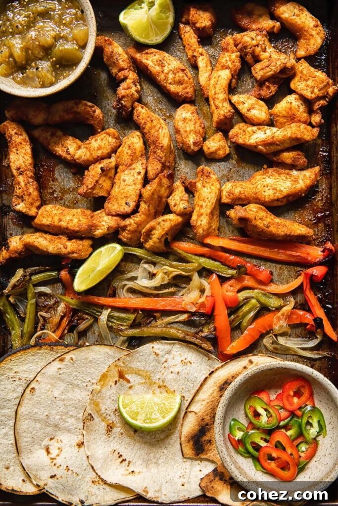 An overhead view of warm tortillas and a variety of fresh fajita toppings arranged appealingly on a baking sheet, ready for serving.