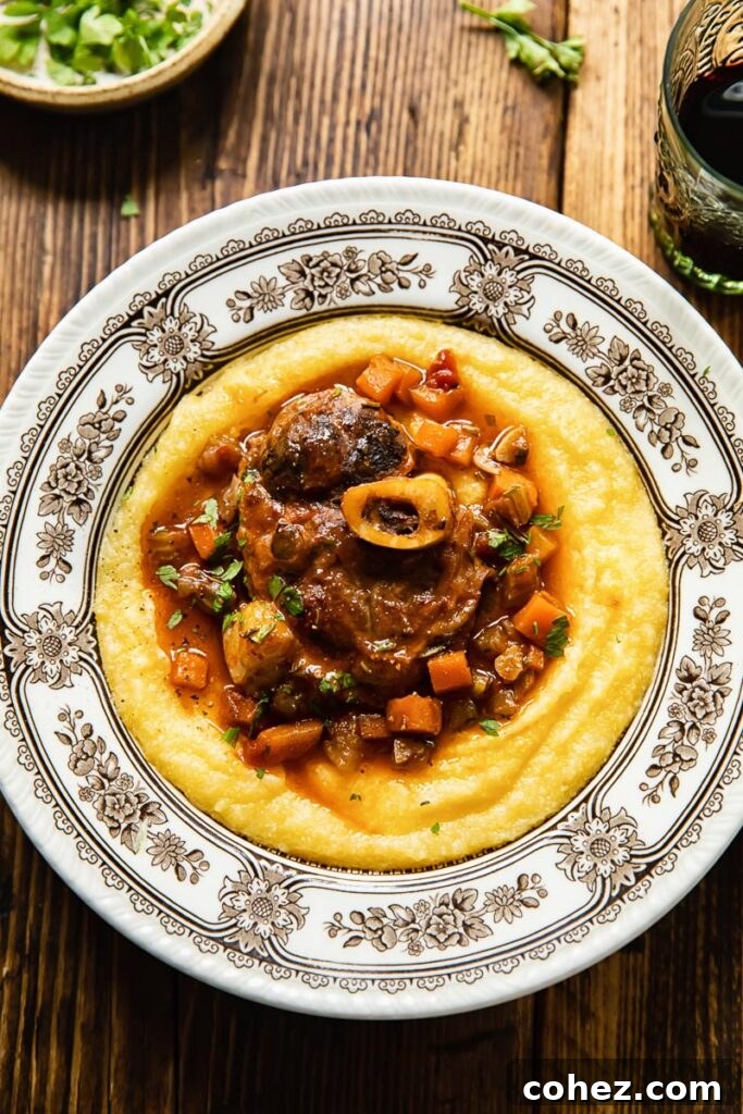Top down view of pork osso buco served over creamy polenta in a bowl, garnished with gremolata