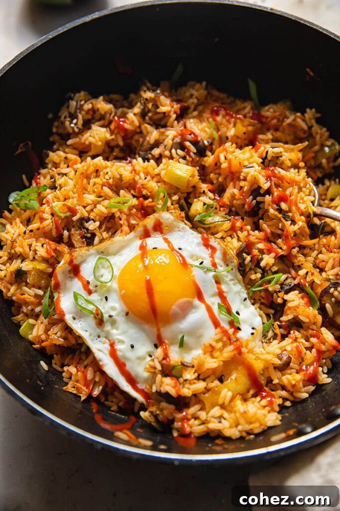 A large wok brimming with steaming Kimchi Fried Rice, garnished with a fried egg, ready to be dished out.