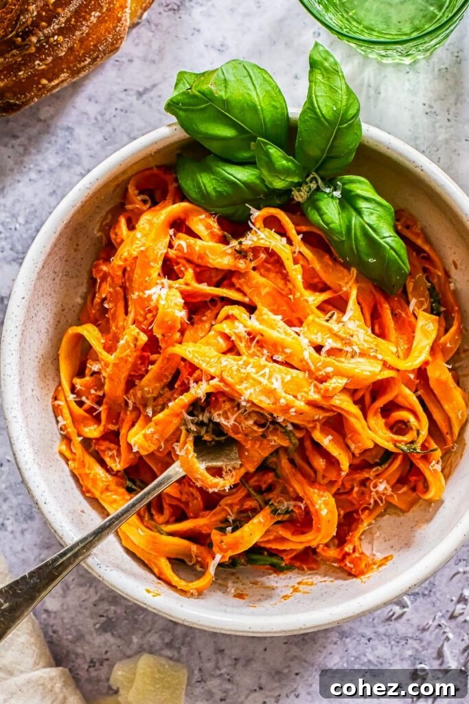 Top down view of a bowl of creamy tomato and mascarpone pasta garnished with fresh basil leaves