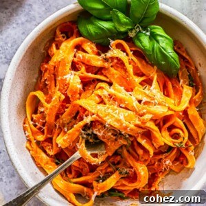 Top down view of a bowl of creamy tomato and mascarpone pasta garnished with fresh basil leaves