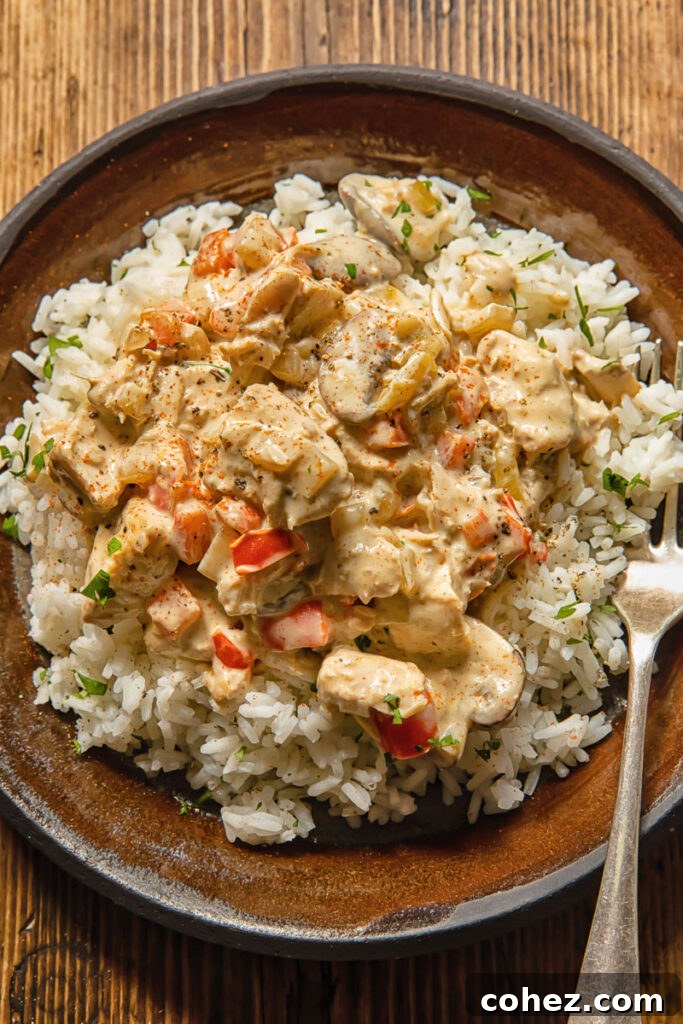 Close up view of white rice topped with turkey a la king on a plate with a fork