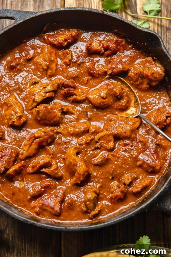 Close-up view of a vibrant chicken Rogan Josh simmering in a pan, ready to be served