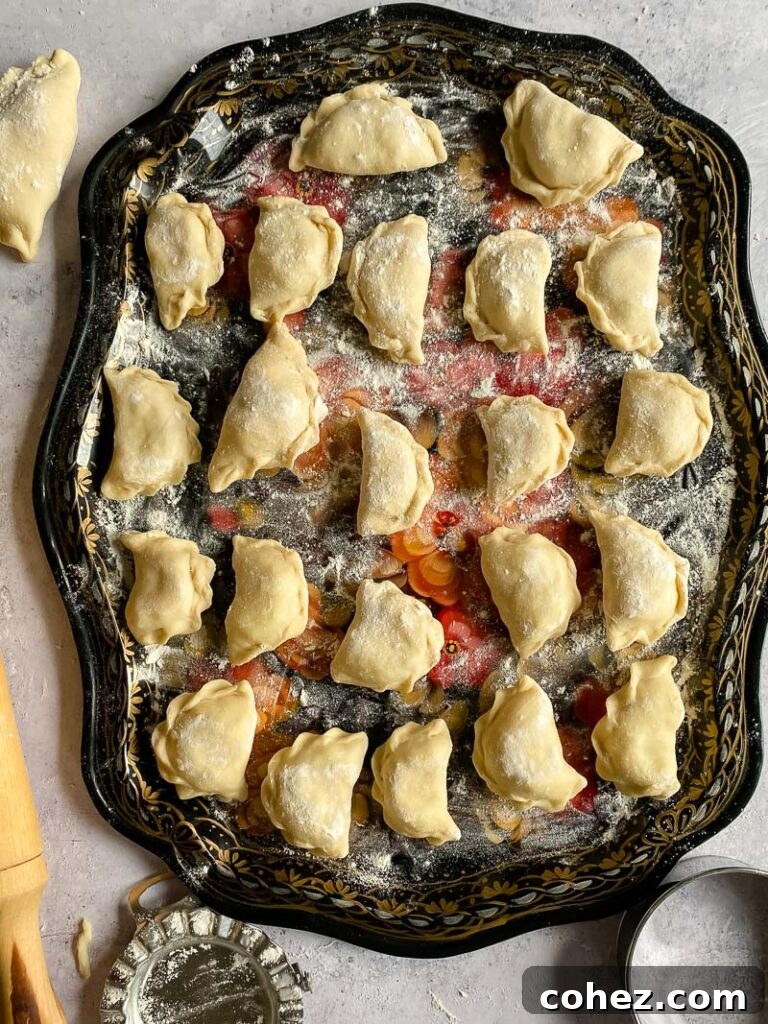 A platter of uncooked potato Pierogi, neatly arranged and ready for boiling.