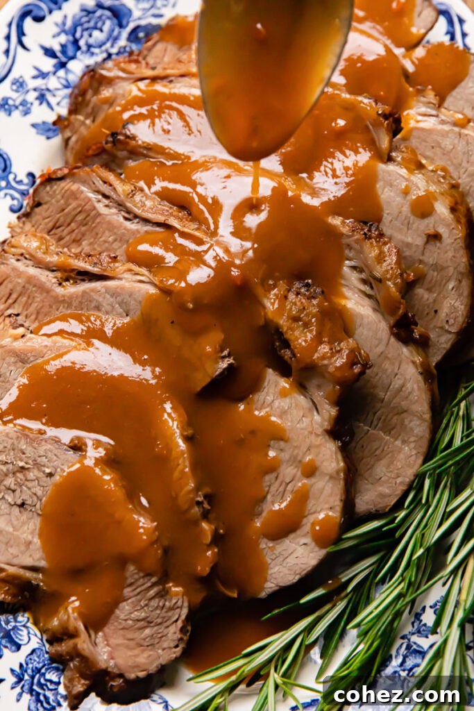 Fall Apart Slow Cooker Roast 4 Close up shot of gravy being drizzled over perfectly sliced slow cooker roast beef on a serving platter