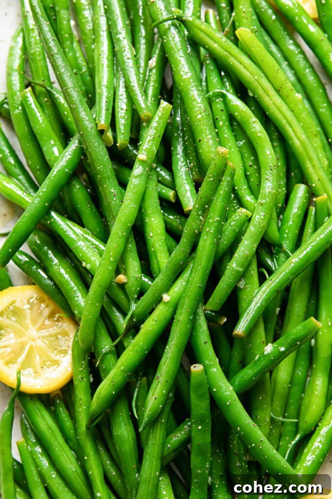 An artfully arranged platter of lemon butter green beans, with visible lemon slices and a focus on texture.