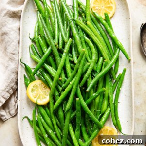 Platter of green beans with lemon butter, with visible lemon slices.