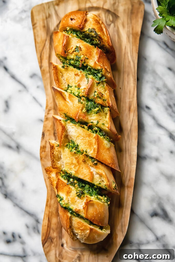 Top down shot of cheesy air fryer garlic bread on a cutting board with fresh parsley scattered around.