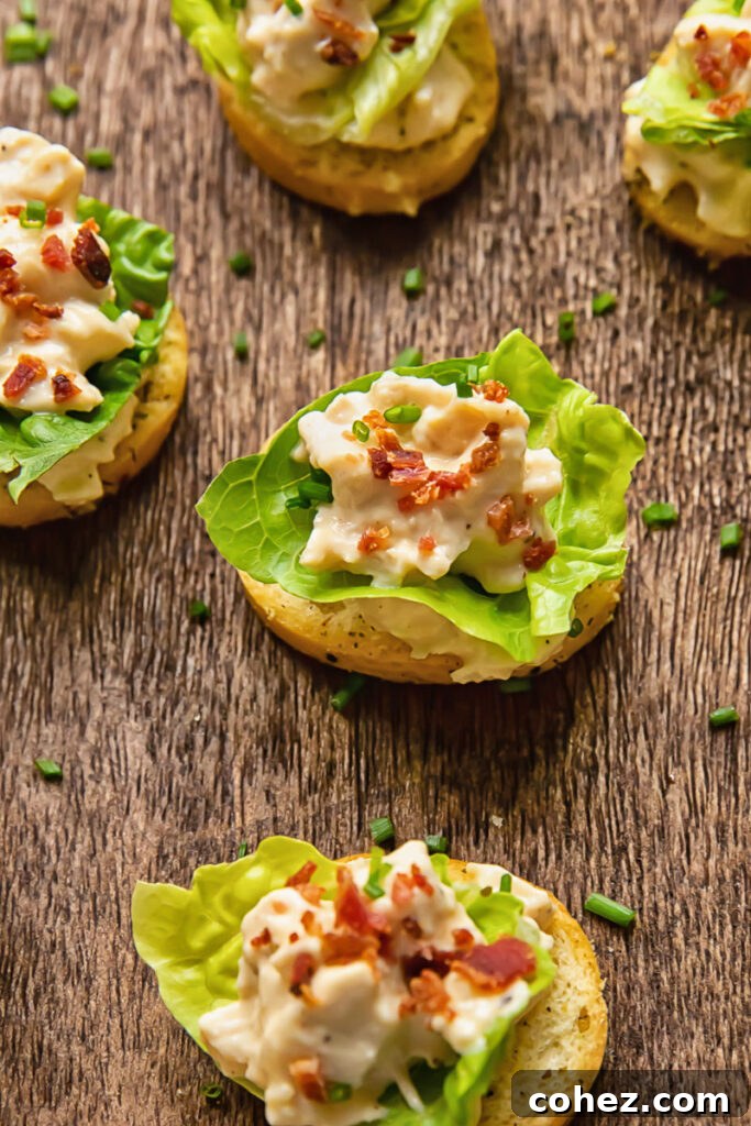 Close up shot of lettuce and chicken Caesar on a crostini on a cutting board