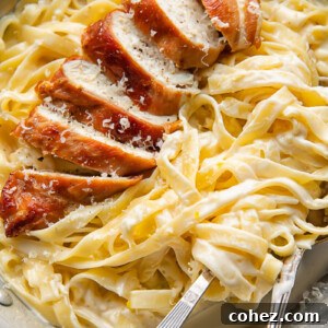 Top down shot of prosciutto wrapped chicken alfredo with creamy fettucine in a bowl with a fork