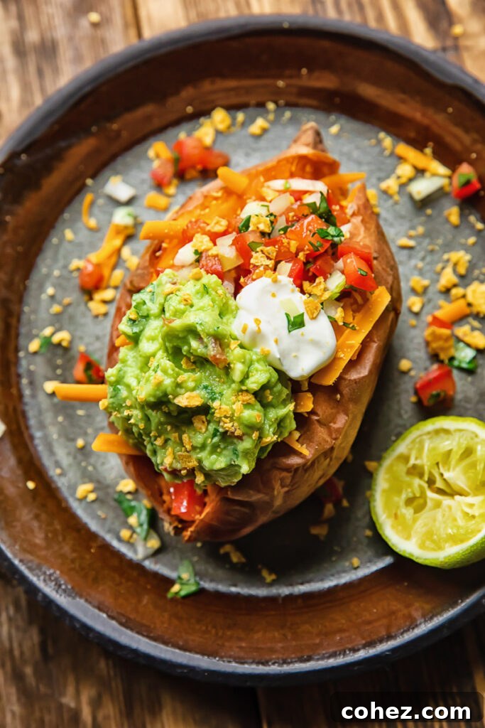 Top down shot of baked sweet potato on a plate topped with pico de gallo and guacamole