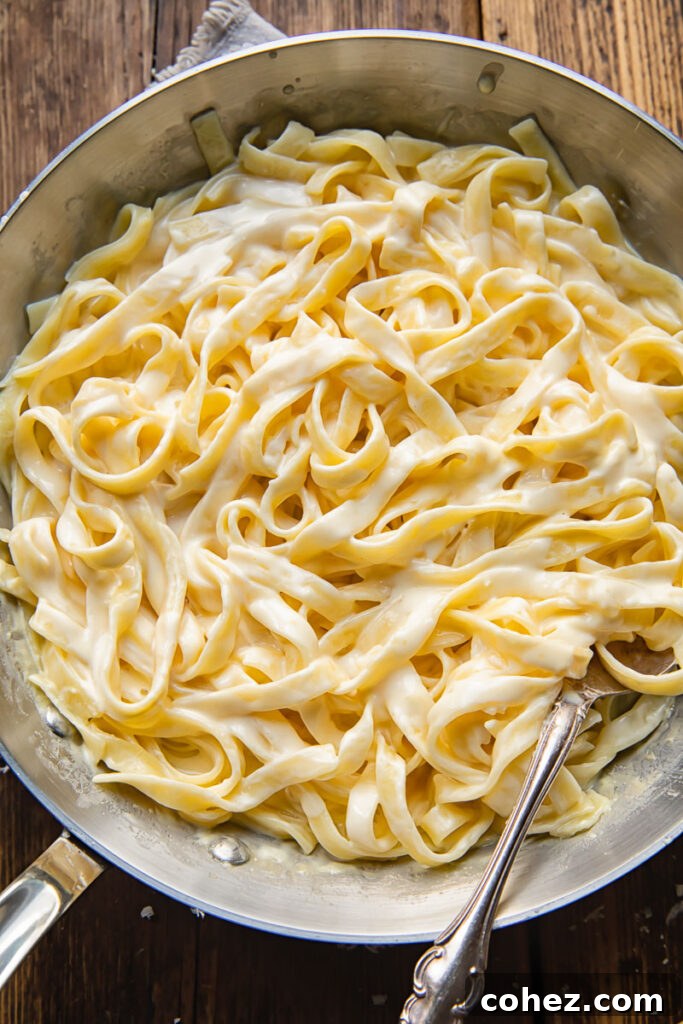 Top down shot of fettucine pasta in a pan with creamy alfredo sauce