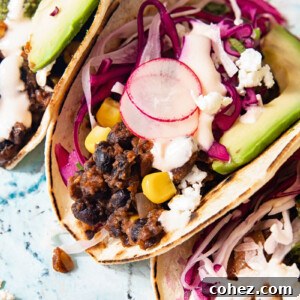 Close up of a black bean and corn taco showing radish and cilantro lime slaw and slice of avocado