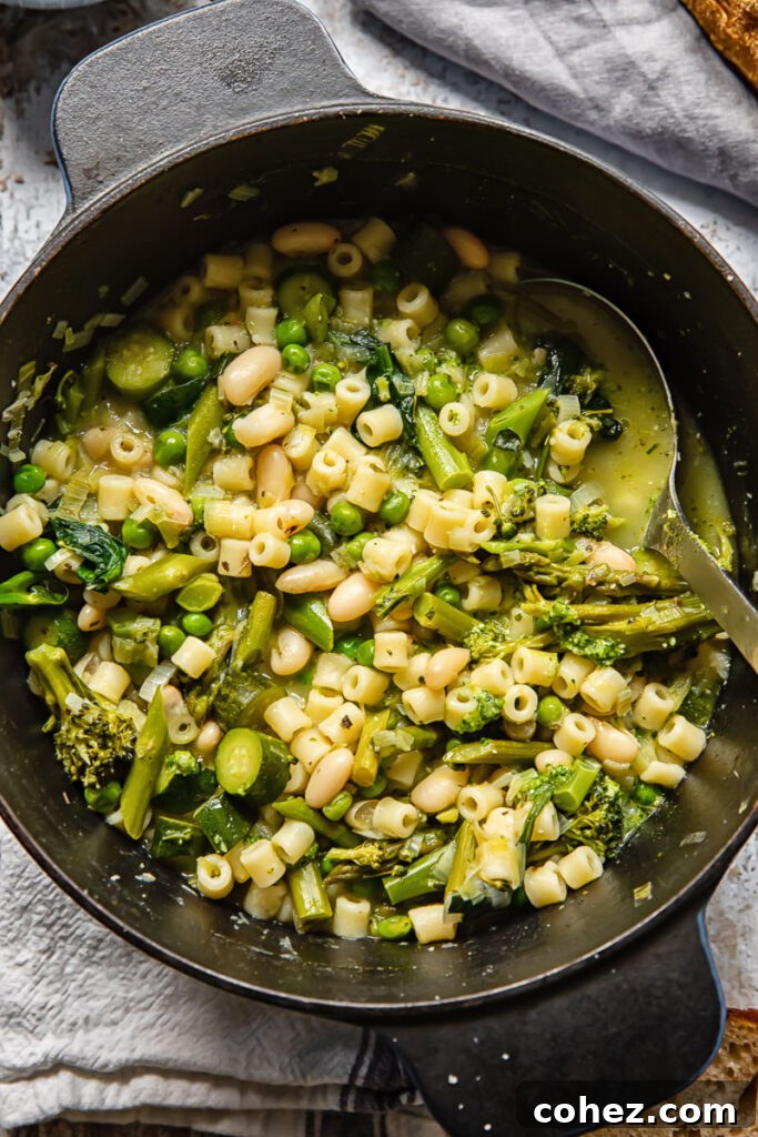 A large pot of spring minestrone soup, photographed from a top-down perspective, showcasing its vibrant green ingredients.