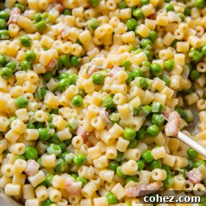 Close up shot of piselli pasta with peas and bacon bits in a large pan