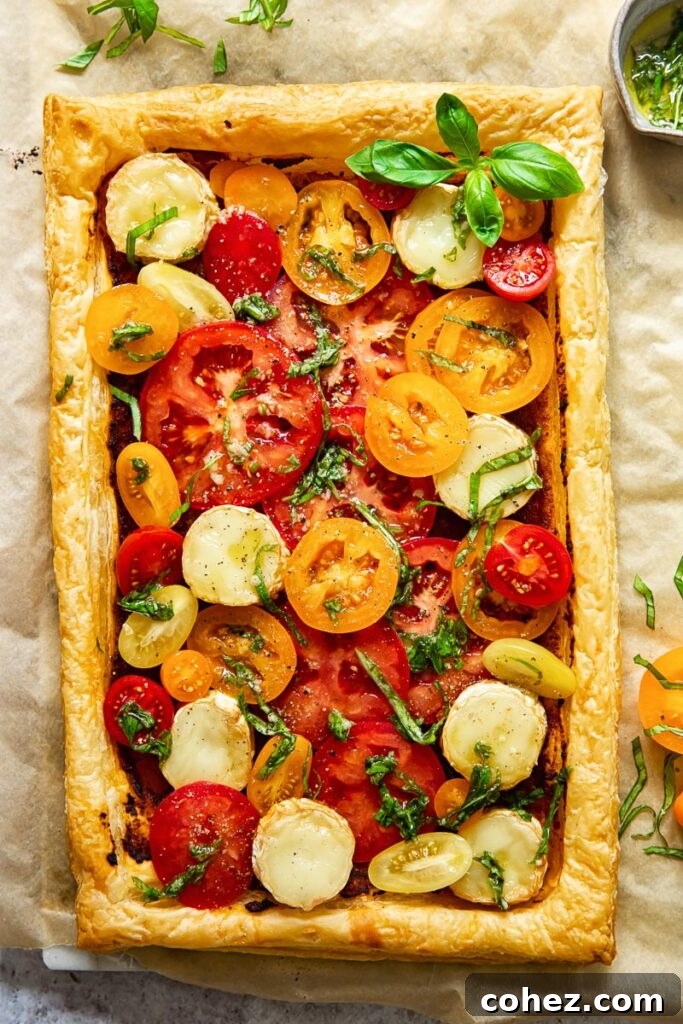 Summer Tomato and Goat Cheese Puff Pastry Tart 4 Overhead shot of the entire golden-baked puff pastry tomato and goat cheese tart, glistening with olive oil and basil, ready to be served.
