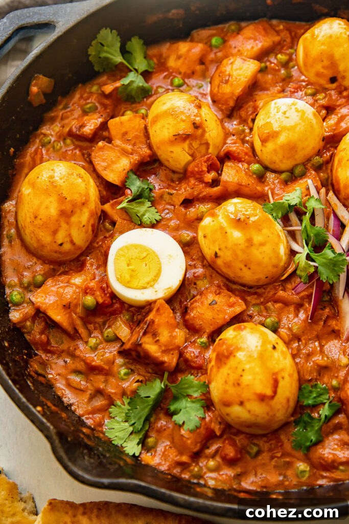 Effortless Egg, Pea, and Potato Curry 3 Close up of egg curry in a frying pan with eggs on top