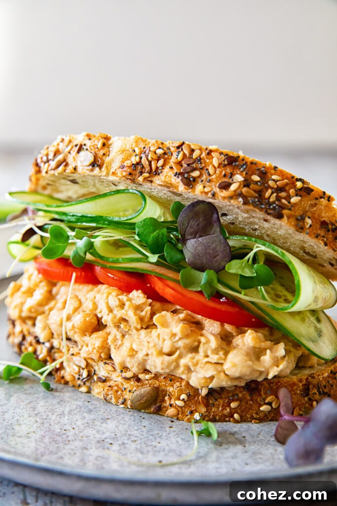 Angled view of chickpea salad sandwich on a plate, showcasing its fresh ingredients and inviting texture.