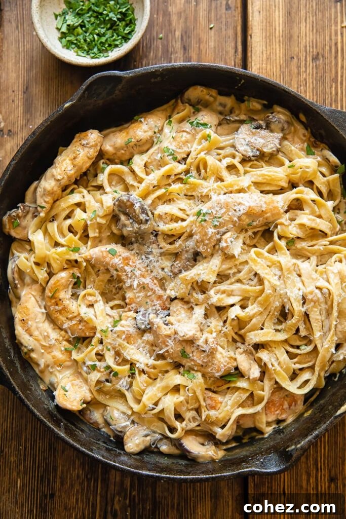 Top down shot of chicken marsala fettuccine in a pan next to a bowl of parsley