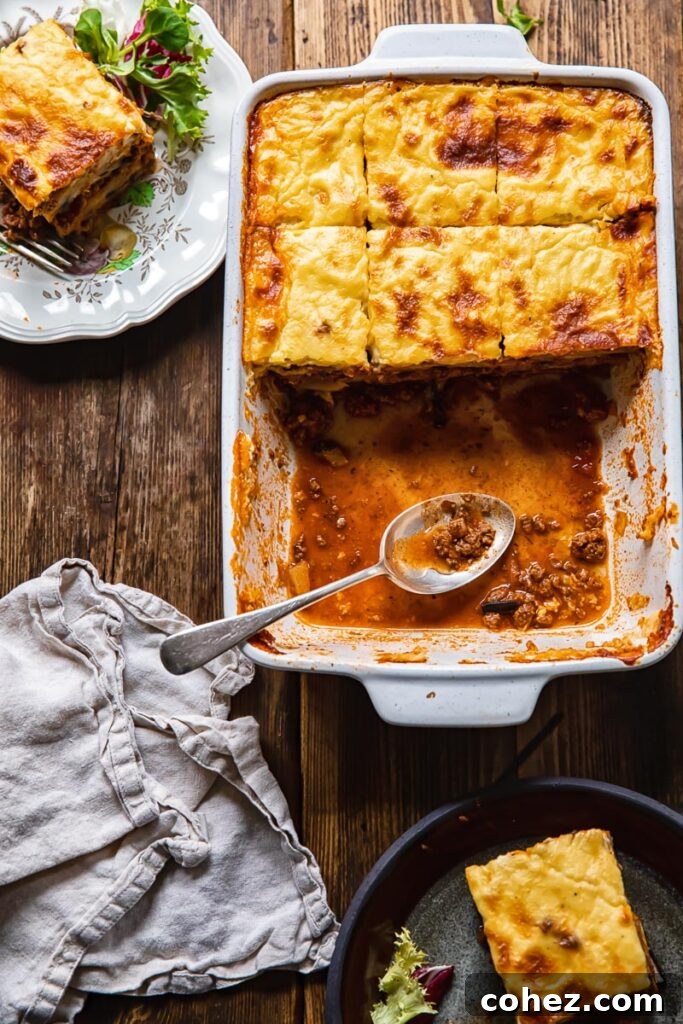 Top down shot of moussaka in a baking dish being served out with a spoon