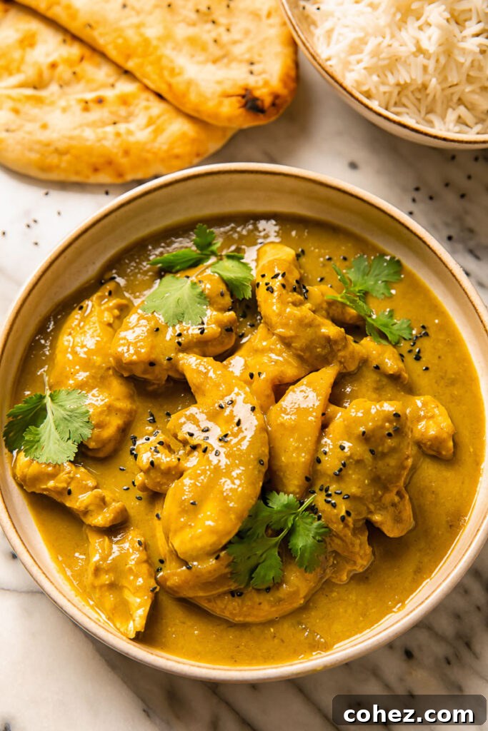 Top down shot of rich mango chicken curry in a bowl topped with fresh cilantro, ready to be served.