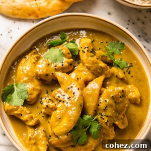 Top down shot of rich mango chicken curry in a bowl topped with fresh cilantro
