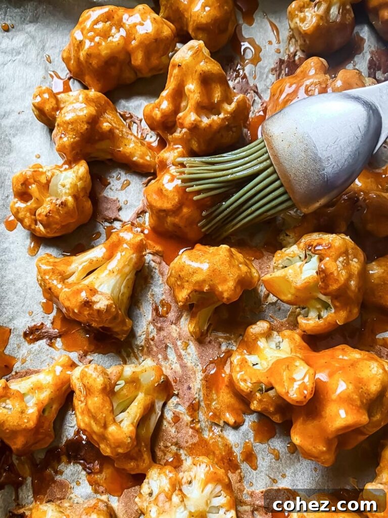 Brush adding buffalo topping to cauliflower