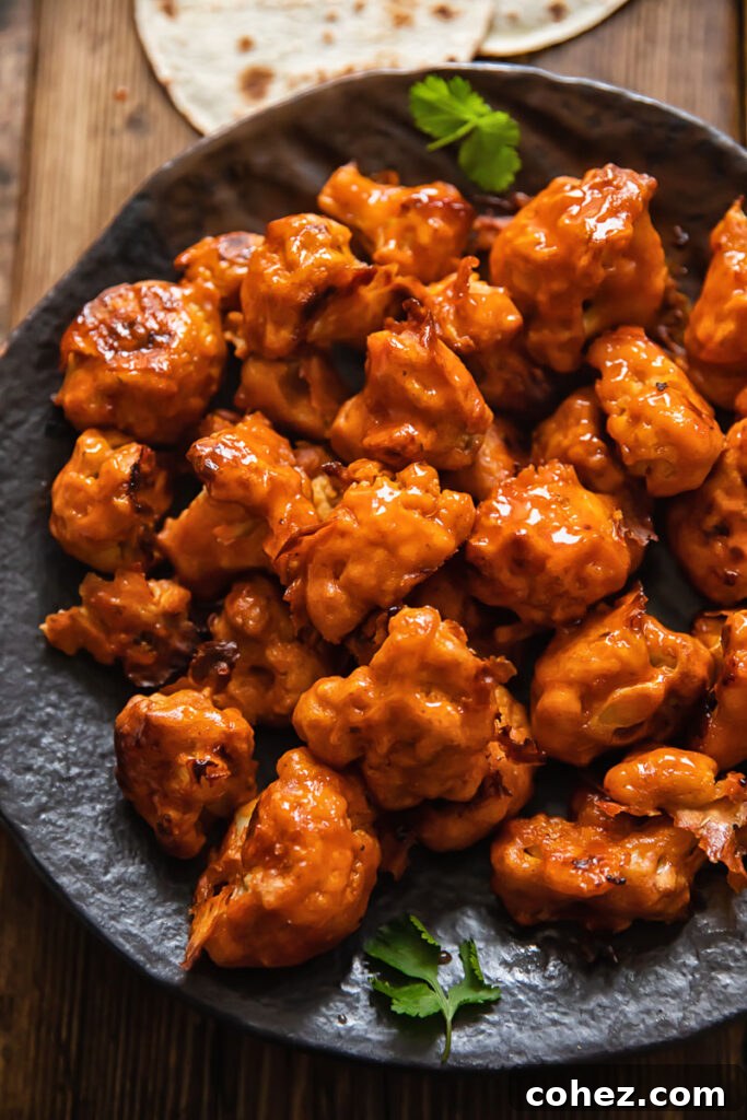 A plate of crispy buffalo cauliflower bites, glistening with sauce
