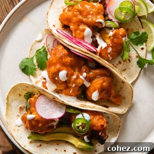 Buffalo cauliflower tacos folded and leaning together on a plate
