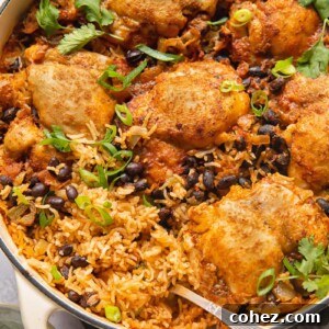 Top down shot of mexican chicken rice in a pan topped with black beans and cilantro