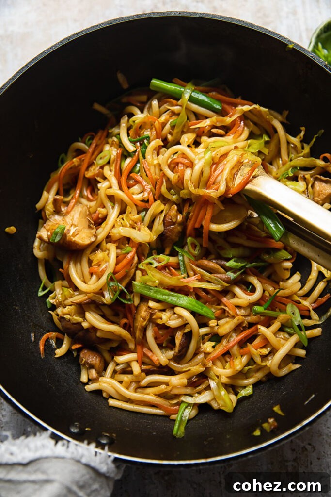 Top down view of a wok with vegetarian yaki udon noodles being stirred