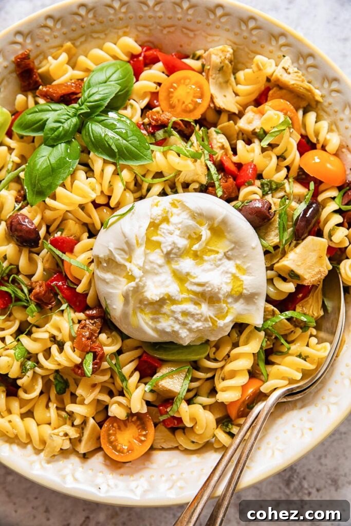 Top down view of a colorful pasta salad bowl topped with a whole burrata
