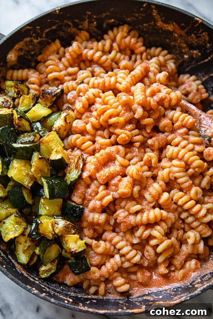 Creamy Tomato Ricotta & Zucchini Pasta for Summer 5 Close-up of a pan containing pasta covered in creamy tomato sauce and fried zucchini pieces