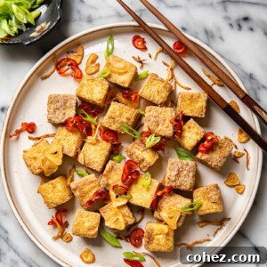 Plate of air fryer tofu bites with chopsticks and side dish of green onions
