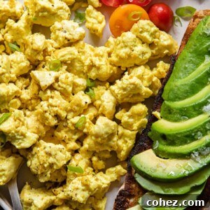 Plate of egg tofu scramble with avocado and tomatoes