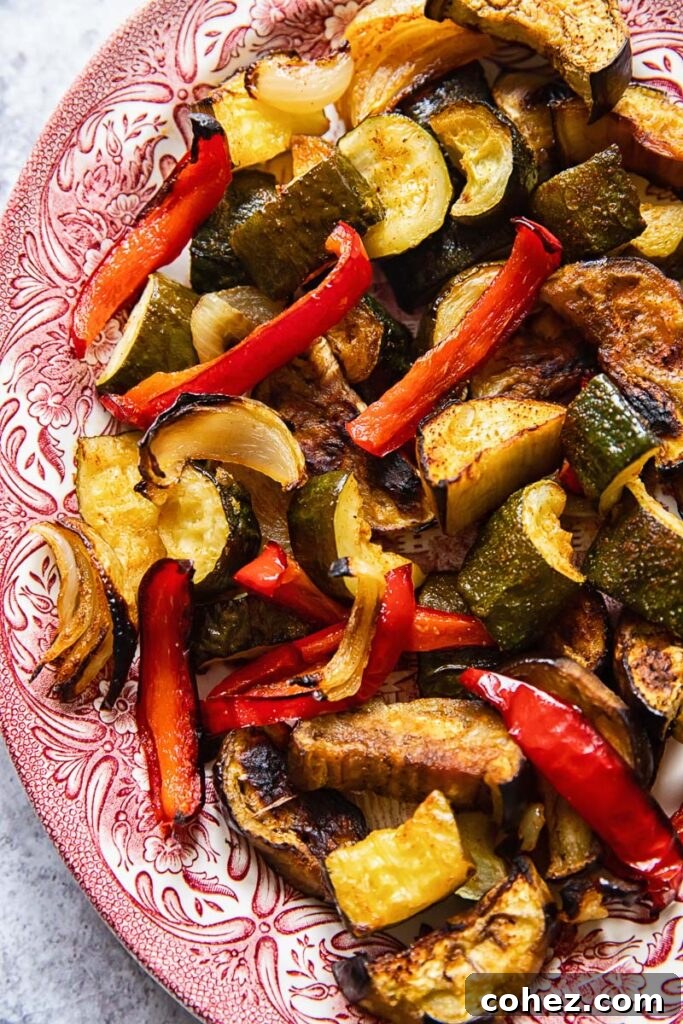 A close-up shot of colorful, perfectly roasted vegetables served on a vibrant pink plate, highlighting their texture and enticing flavors.