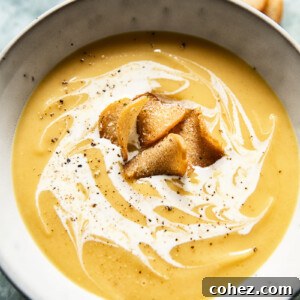 A vibrant bowl of curried roasted parsnip soup, garnished with fresh herbs and croutons, ready to be served.
