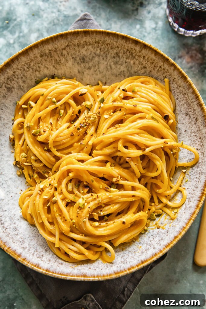 A beautifully presented bowl of roasted butternut squash pasta, generously topped with a crunchy pistachio crumb, ready to be enjoyed.