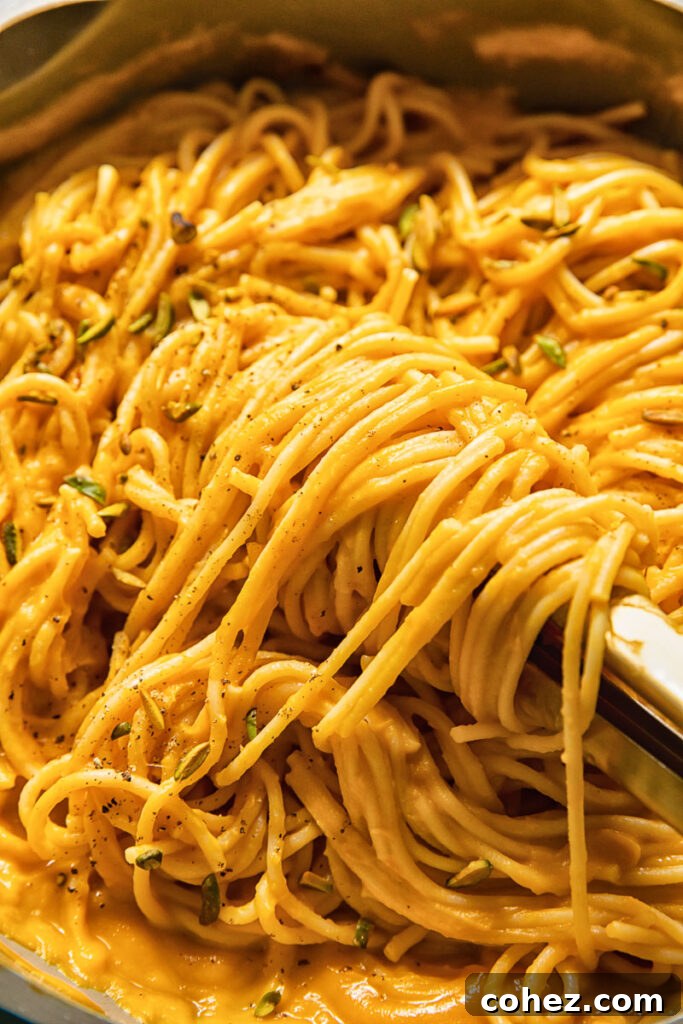 A close-up shot revealing the rich, creamy texture of the butternut squash sauce coating the pasta, adorned with specks of green pistachio.