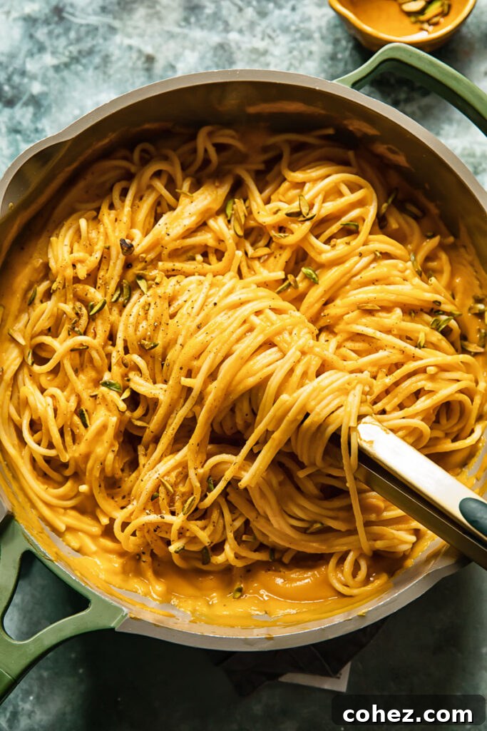 A top-down view of a pan filled with roasted butternut squash pasta, showcasing the abundance of the creamy sauce and pasta strands.