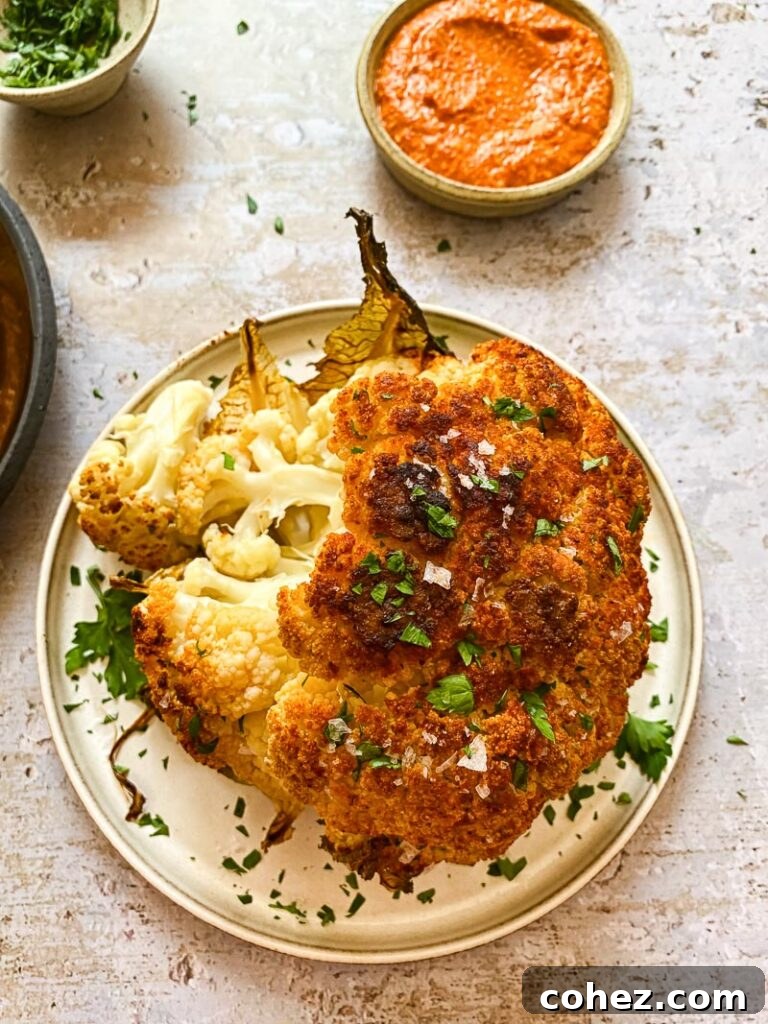 Roasted whole cauliflower on a plate from the top down, with romesco sauce