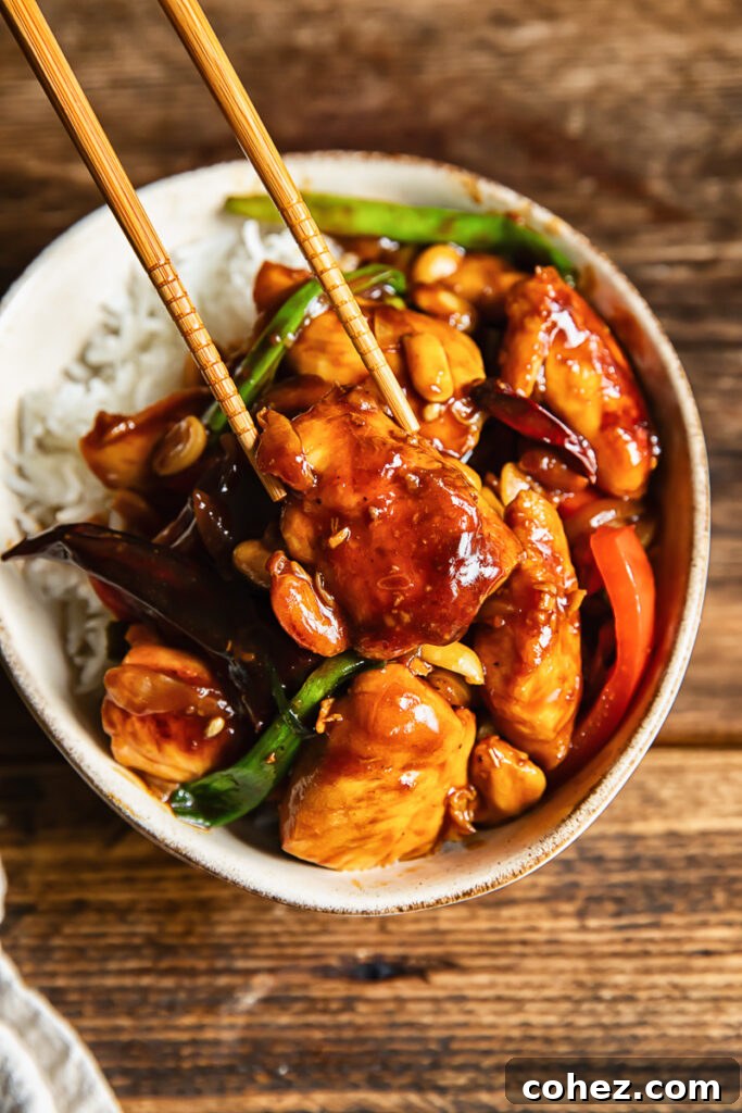 Close up shot of piece of chicken being picked up with chopsticks from szechuan stir fry
